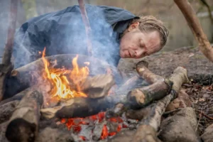 Persona encendiendo fuego en la naturaleza utilizando técnicas de supervivencia