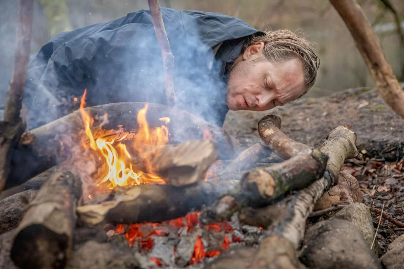 Persona encendiendo fuego en la naturaleza utilizando técnicas de supervivencia